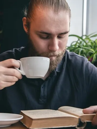 Man drinking tea and reading a book at a café