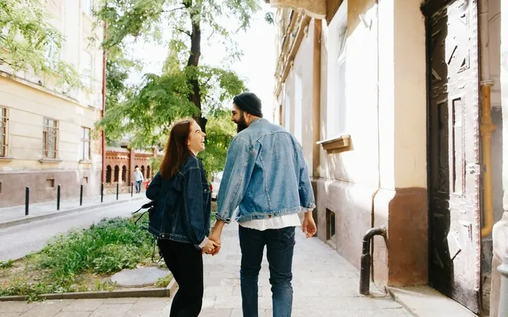 A man and a woman walking hand in hand down an old street