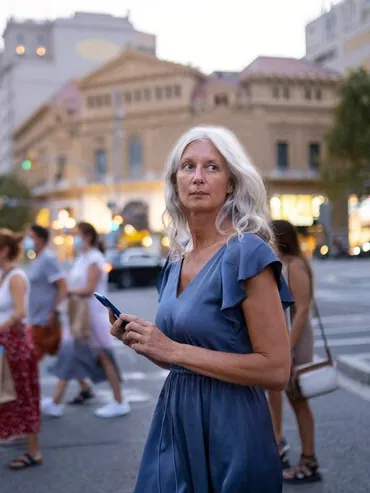 Grey-haired woman walking along a busy street in the city centre
